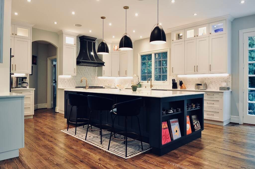 Remodeled white kitchen with a navy island and black pendant lights